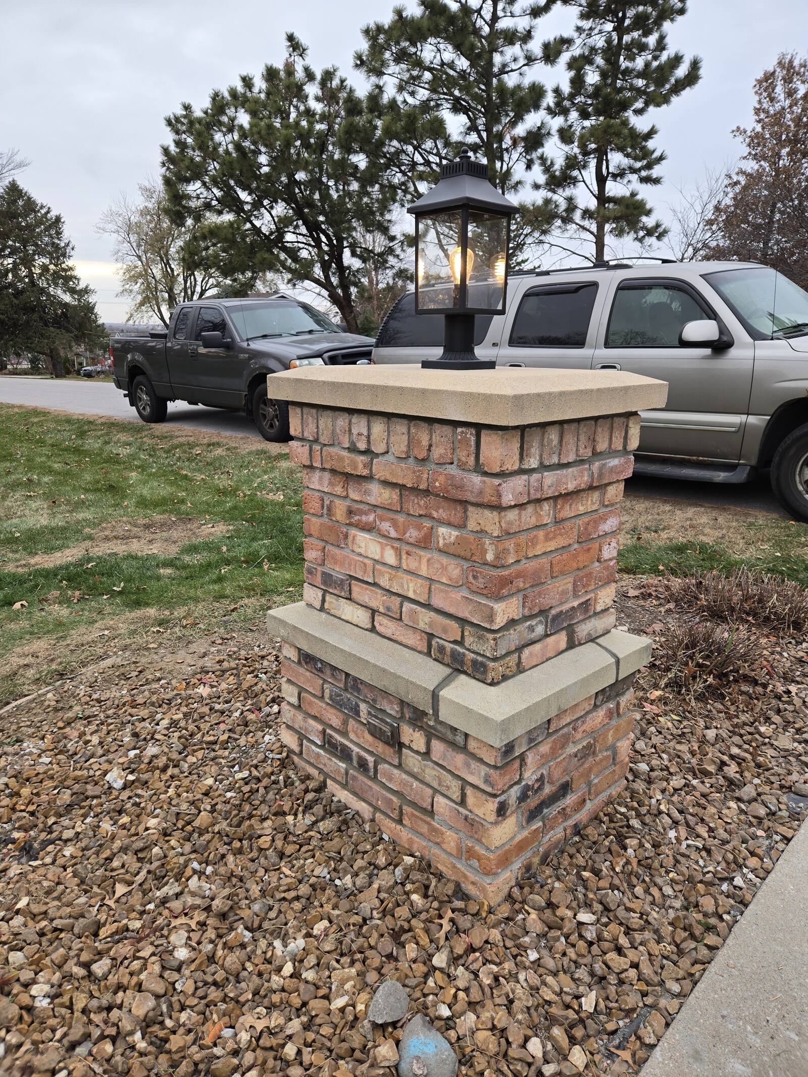 Brick and stone driveway pillar with cap and lantern