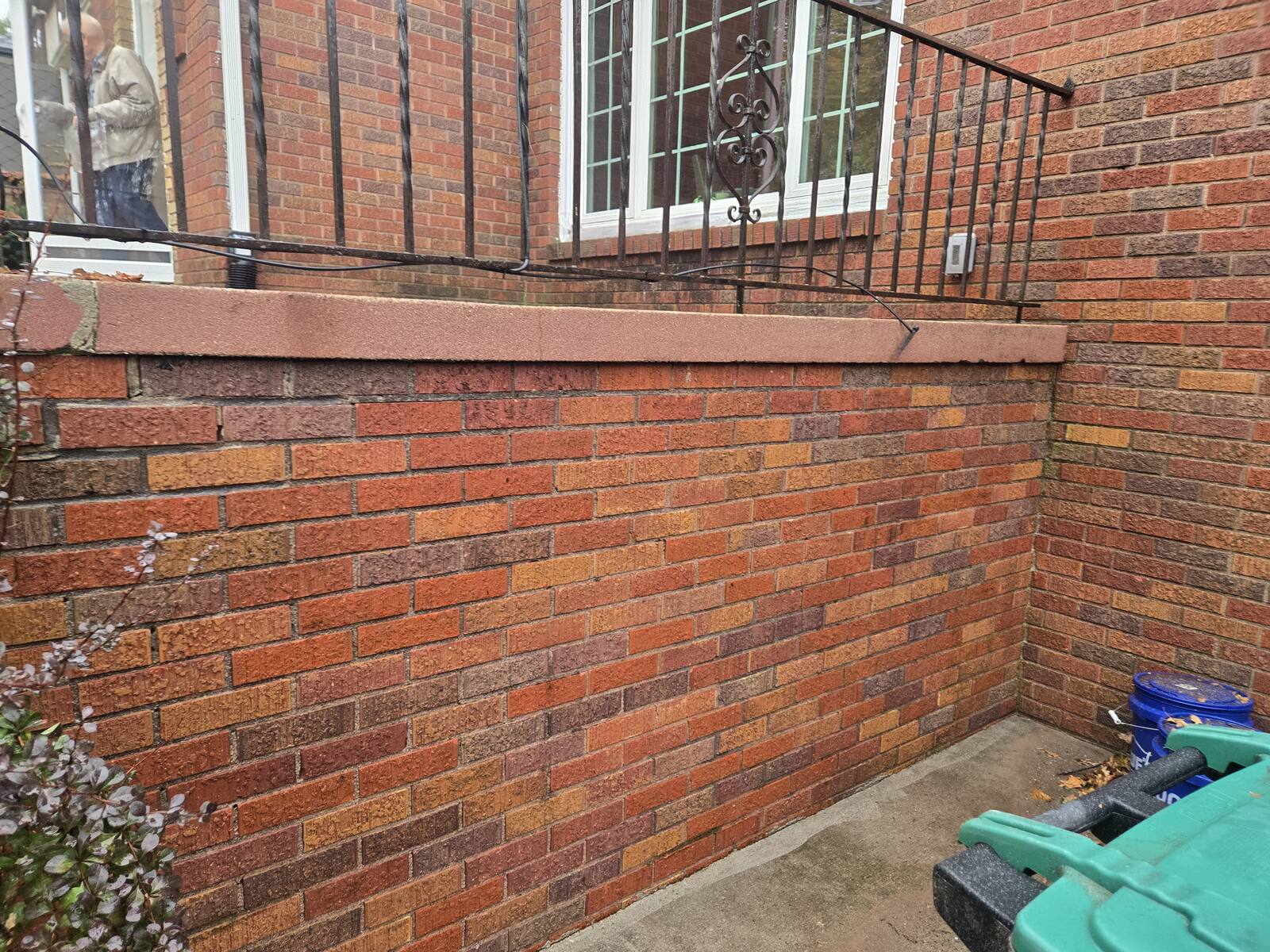 Brick retaining wall below a window with iron railing